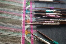 Little wooden sticks with colorful threads on a Kani weaving loom