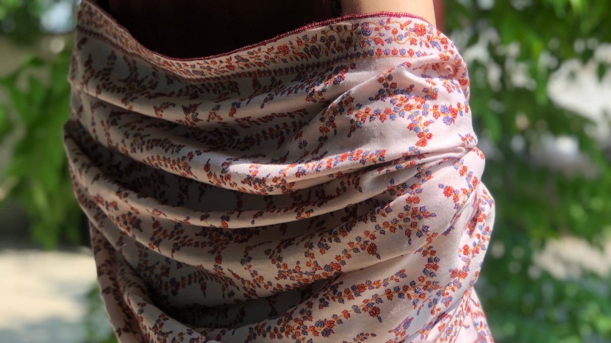 A female model wearing a baby pink embroidery pashmina shawl 